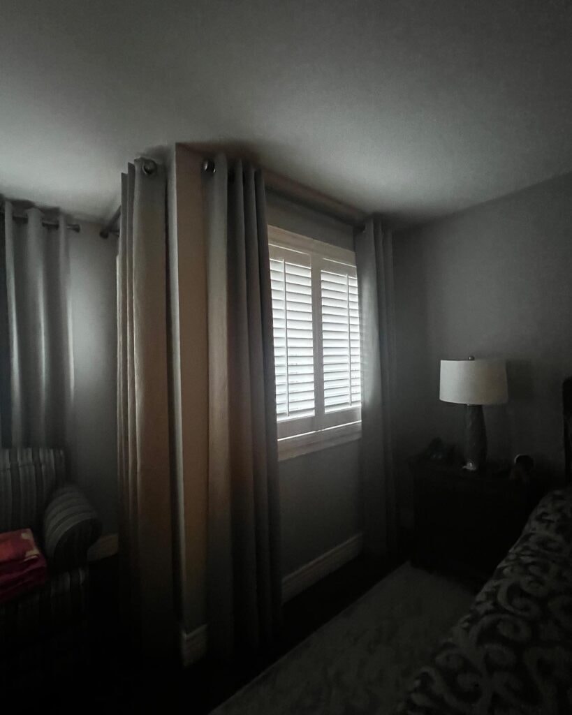 Bedroom window with grey grommet drapes and shutters
