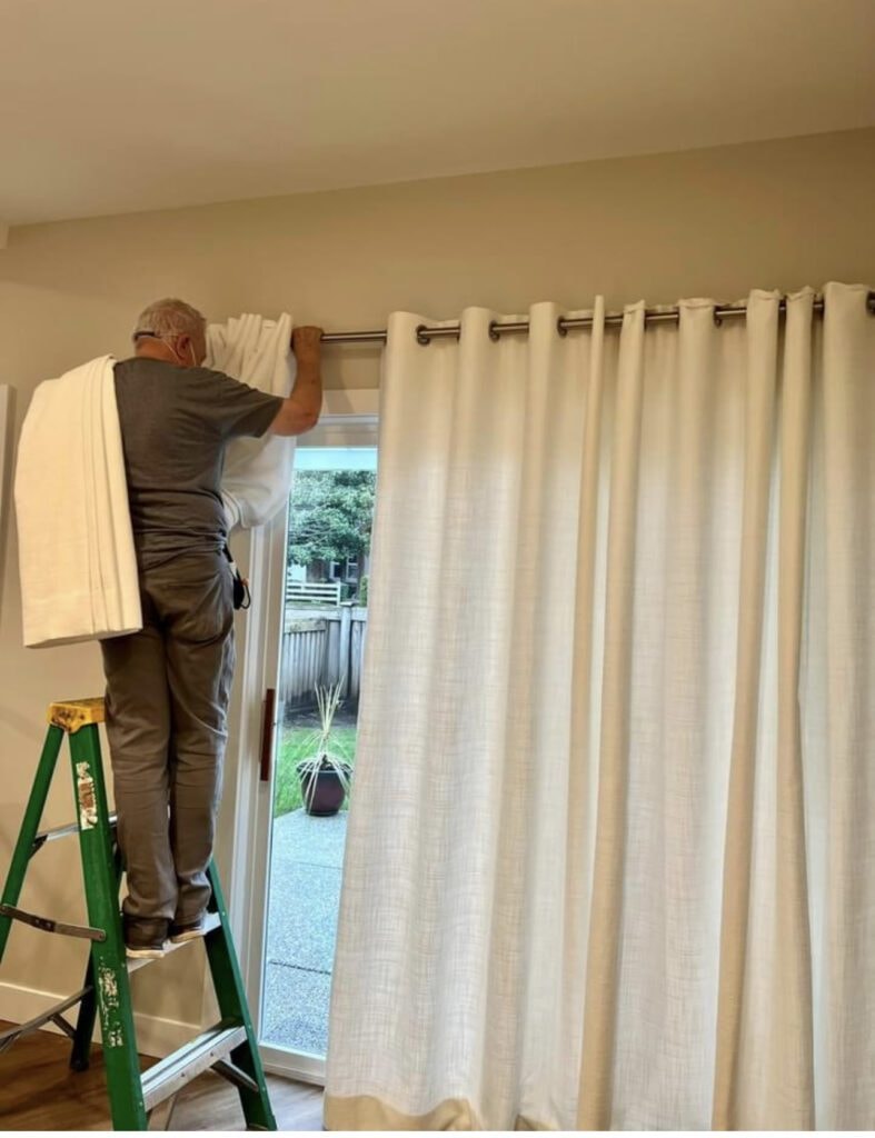 Installer hanging cream grommet drapes on sliding door