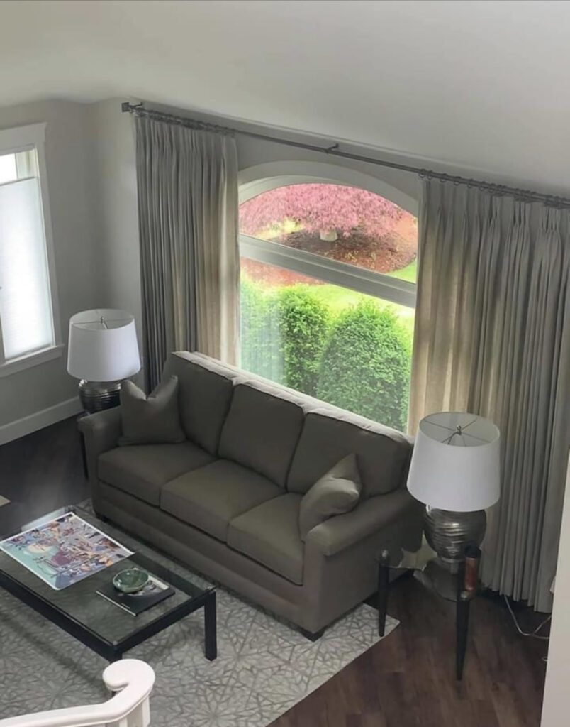 Grey pinch pleat drapes in living room with arched window