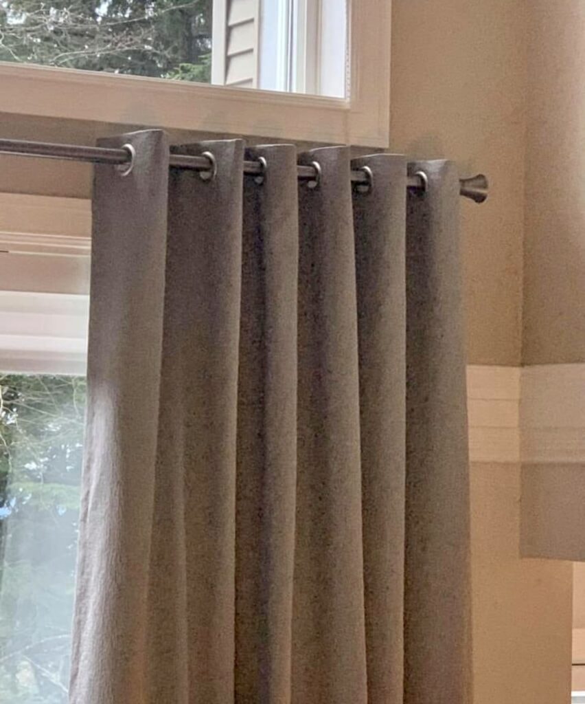 Taupe grommet curtains close-up on rod