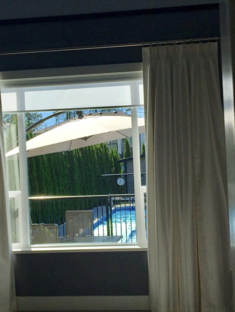 Cream drapes with roller blind overlooking pool and garden