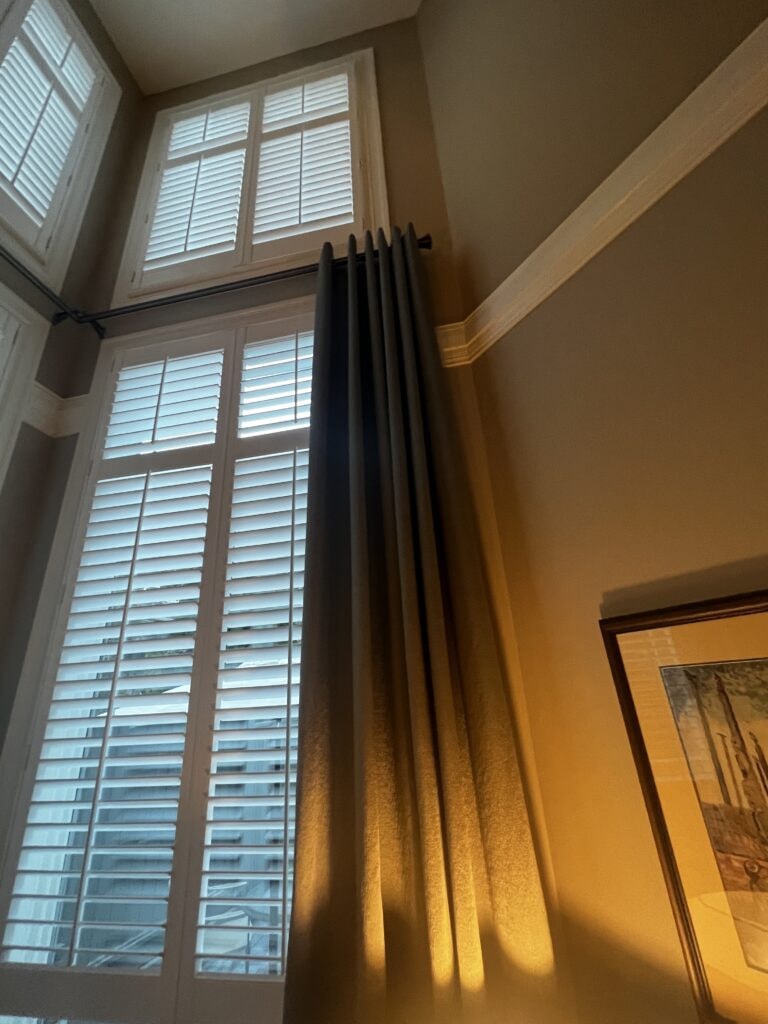 Dark grommet drapes with tall plantation shutters