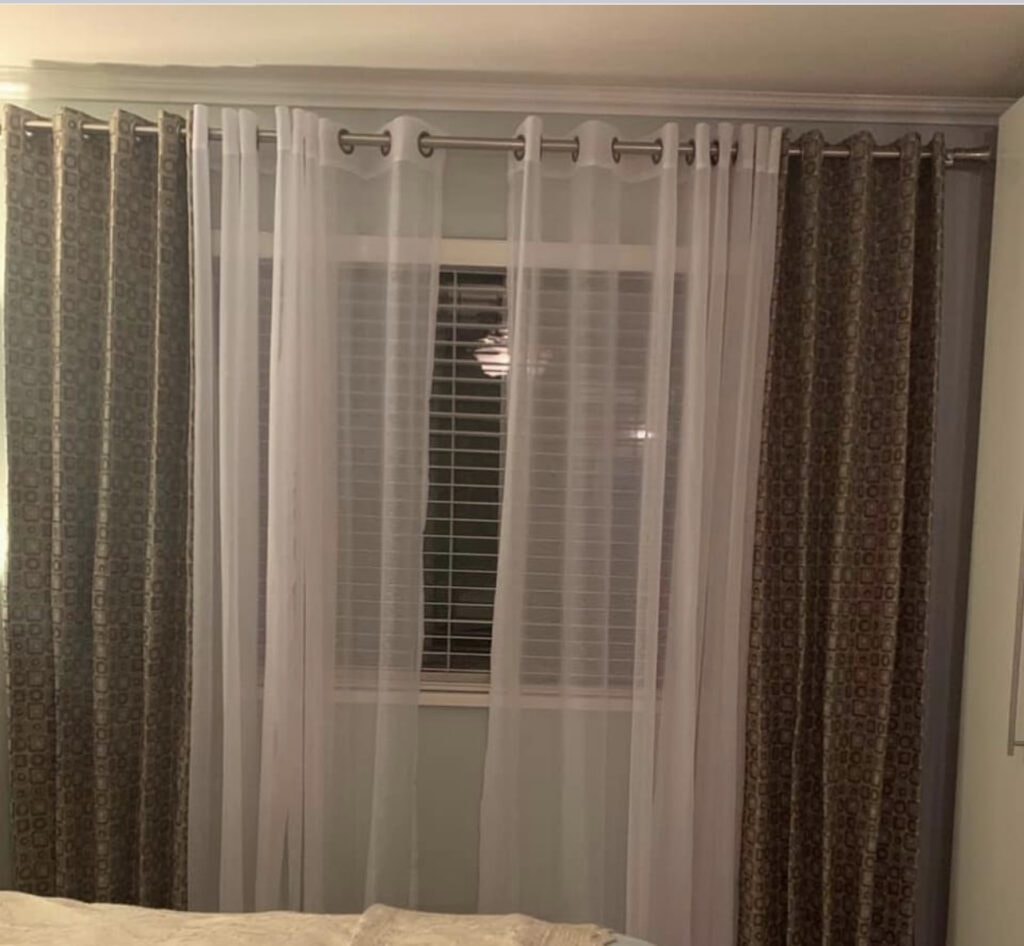 Layered sheer and patterned drapes in bedroom